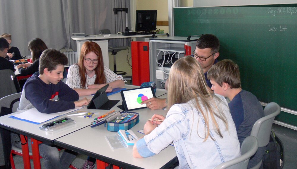 Groupe travaillant sur des tablettes autour d'une table